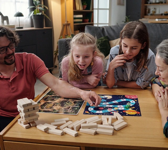 Family plays board games together at home, cozy atmosphere with parents and children enjoying fun and interaction around the table.
